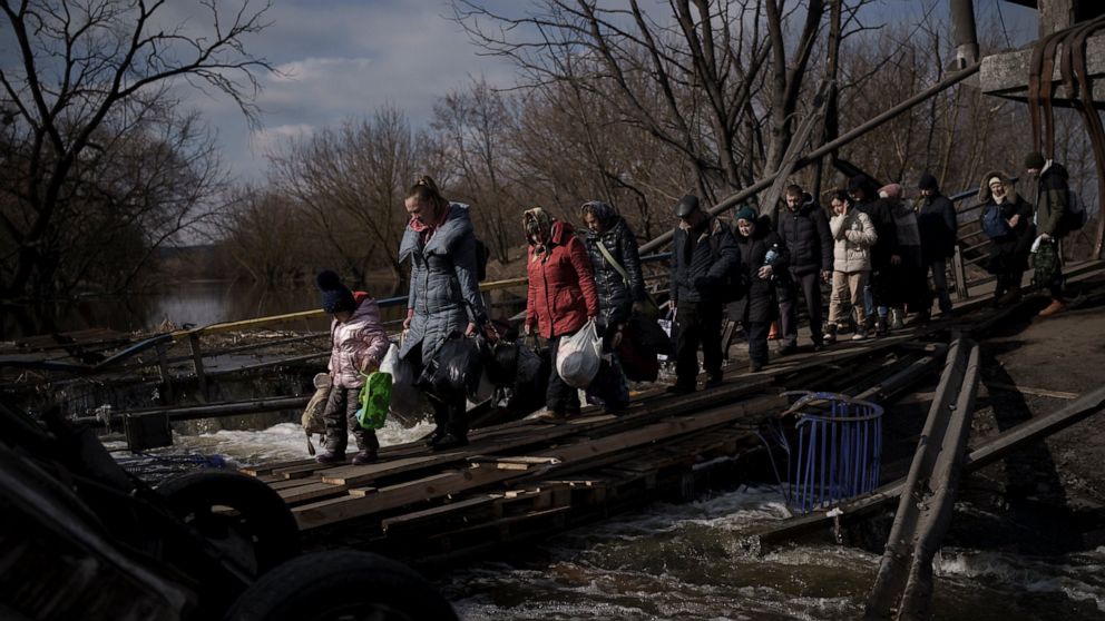 Ukrainians cross an improvised path under a destroyed bridge while fleeing Irpin, on the outskirts of Kyiv, Ukraine, Wednesday, March 9, 2022. (AP Photo/Felipe Dana)