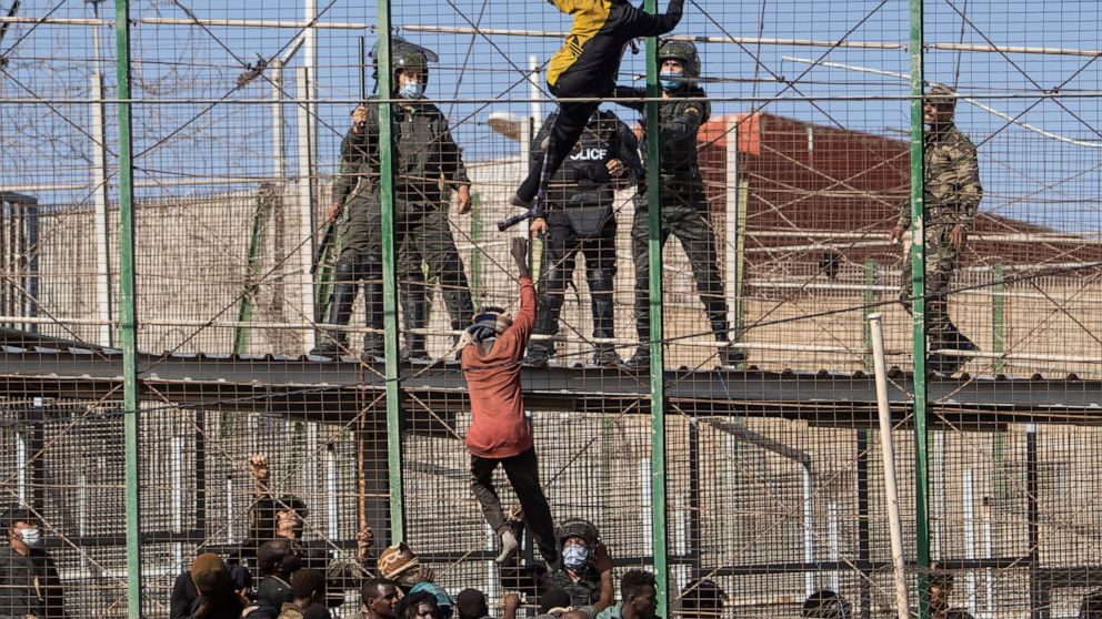 Migrants climb the fences separating the Spanish enclave of Melilla from Morocco in Melilla, Spain, Friday, June 24, 2022. Dozens of migrants stormed the border crossing between Morocco and the Spanish enclave city of Melilla on Friday in what is the