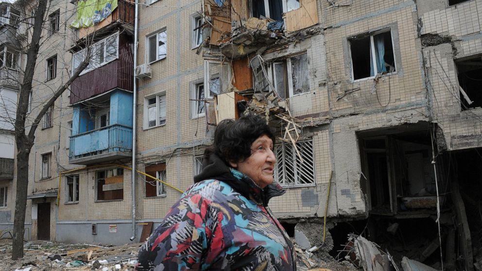 A woman walks past an apartment building damaged by shelling in Kharkiv, Ukraine, Sunday, April 10, 2022. (AP Photo/Andrew Marienko)