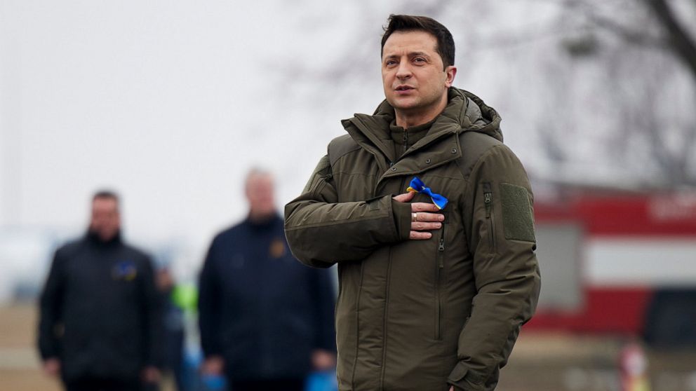 In this handout photo provided by the Ukrainian Presidential Press Office, Ukrainian President Volodymyr Zelenskyy listens to Ukrainian national anthem as he takes part in celebration of the Day of the Unit at an international airport outside Kyiv, U