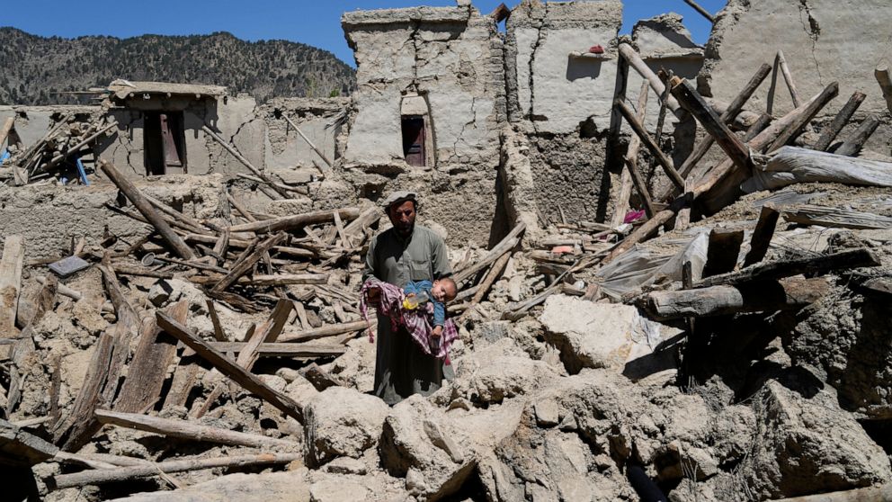 Afghan man carries his child amid destruction after an earthquake in Gayan village, in Paktika province, Afghanistan, Friday June 24, 2022. A powerful earthquake struck a rugged, mountainous region of eastern Afghanistan early Wednesday, flattening s