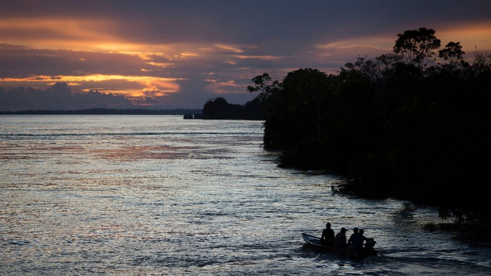 FILE - In this May 22, 2014 file photo, a small boat navigates on the Solimoes River near Manaus, Brazil. In the remote Amazon community of Betania, indigenous Tikuna tribe members suspect the new coronavirus arrived in May of 2020 after some returne