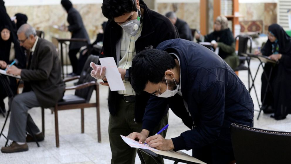 Voters with face masks fill out their ballots in the parliamentary elections at a polling station in Tehran, Iran, Friday, Feb. 21, 2020. Iranians began voting for a new parliament Friday, with turnout seen as a key measure of support for Iran's lead