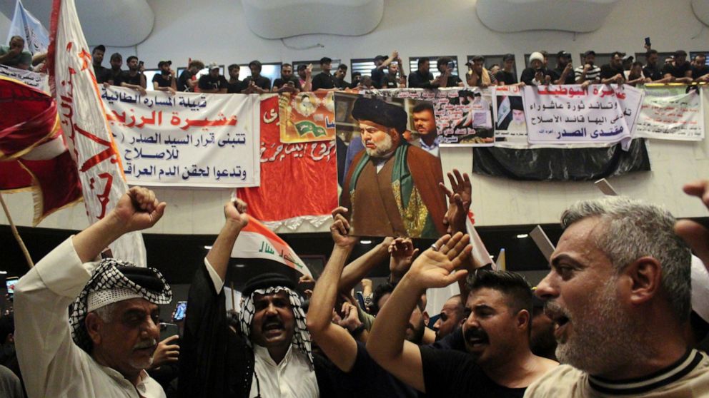 Followers of Shiite cleric Muqtada al-Sadr hold posters with his photo during a sit-in, inside the parliament in Baghdad, Iraq, Tuesday, Aug. 2, 2022. (AP Photo/Adil al-Khazali)