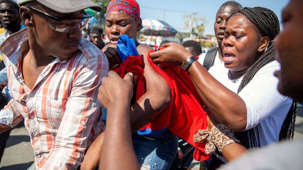 An injured protester is helped by others during a protest to demand the resignation of Haiti's president Jovenel Moise in Port-au-Prince, Haiti, Wednesday, Jan. 20, 2021. Moise has one more year in power, but a growing groundswell of opposition is or