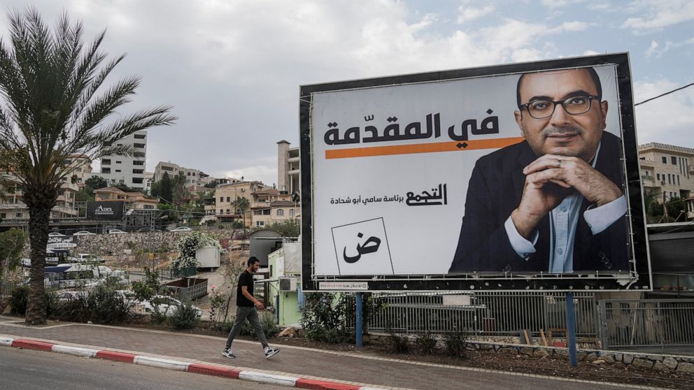 A man walks by an election campaign billboard showing Sami Abu Shehadeh, head of the nationalist Balad party, in the northern Israeli city of Umm al-Fahm, Friday, Oct. 21, 2022. Israel’s Palestinian citizens, a minority whose voice is often drowned o