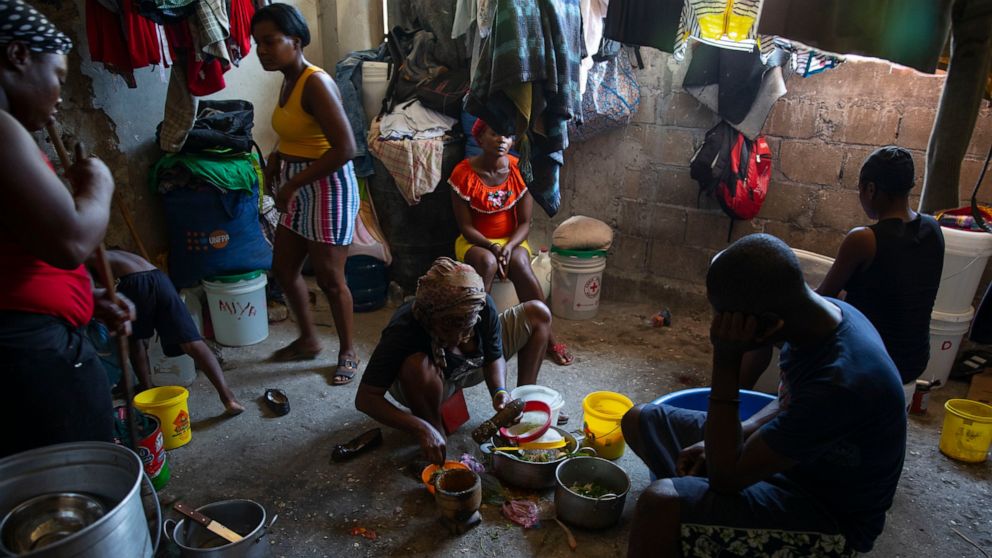 A woman prepares food at a shelter for families displaced by gang violence in Port-au-Prince, Haiti, Thursday, Dec. 9, 2021. A spike in violence has deepened hunger and poverty in Haiti while hindering the very aid organizations combating those probl