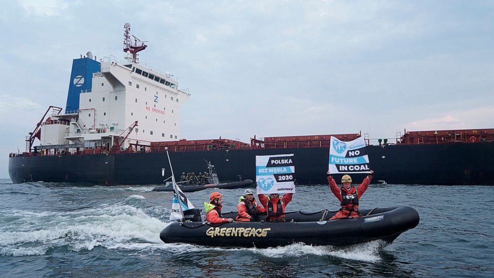 In this Monday, Sept. 9, 2019 photo provided by the environment group Greenpeace activists of Greenpeace are seen in boats with anti-coal slogans, trying to block a cargo ship with coal from Mozambique to enter the port in Gdansk, Poland. Armed and m