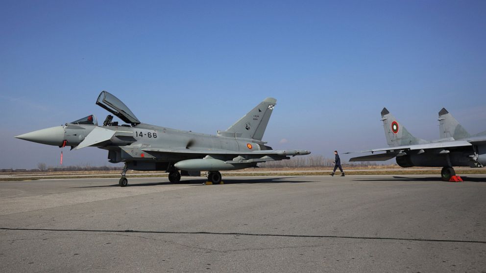A military officer is passing between Bulgaria's MiG-29 and Spanish Eurofighter EF-2000 Typhoon II aircraft and MiG-29, in Graf Ignatievo, Thursday, Feb. 17, 2022.. As part of the united efforts of NATO partners to bolster the defense of the Alliance
