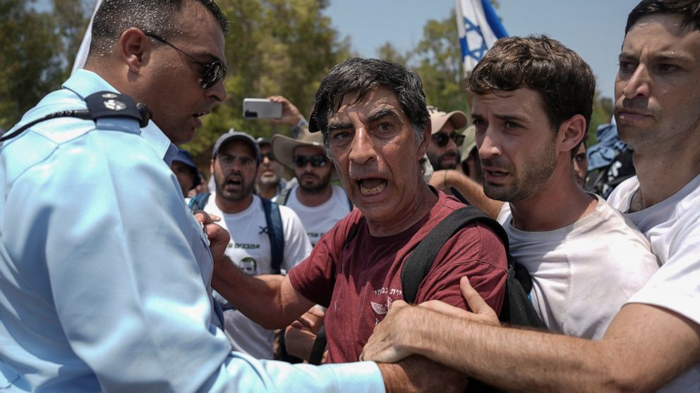 An Israeli police officer tries to block Simha Goldin, center, father of Israeli soldier Hadar Goldin, killed during the 2014 conflict in the Gaza Strip, from marching towards the Gaza border near Kibbutz Yad Mordechai, southern Israel Friday, Aug. 5