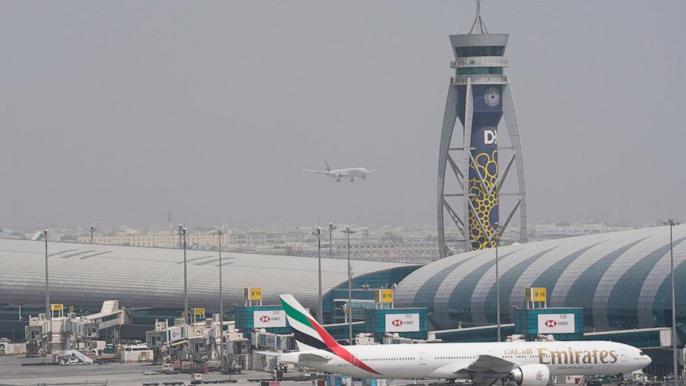 FILE- An Emirates Boeing 777 stands at the gate at Dubai International Airport as another prepares to land on the runway in Dubai, United Arab Emirates, Wednesday, Aug. 17, 2022. Emirates will suspend all flights to Nigeria from September 1 over its 