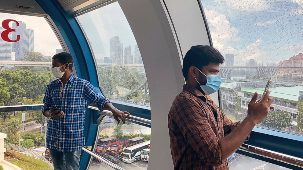 Migrant worker Natarajan Pandiarajan, right, enjoys the view on board the Singapore Flyer attraction in Singapore on March 7, 2021. He is among at least 20,000 migrant workers who will be treated to rides by members of the public and businesses. Migr