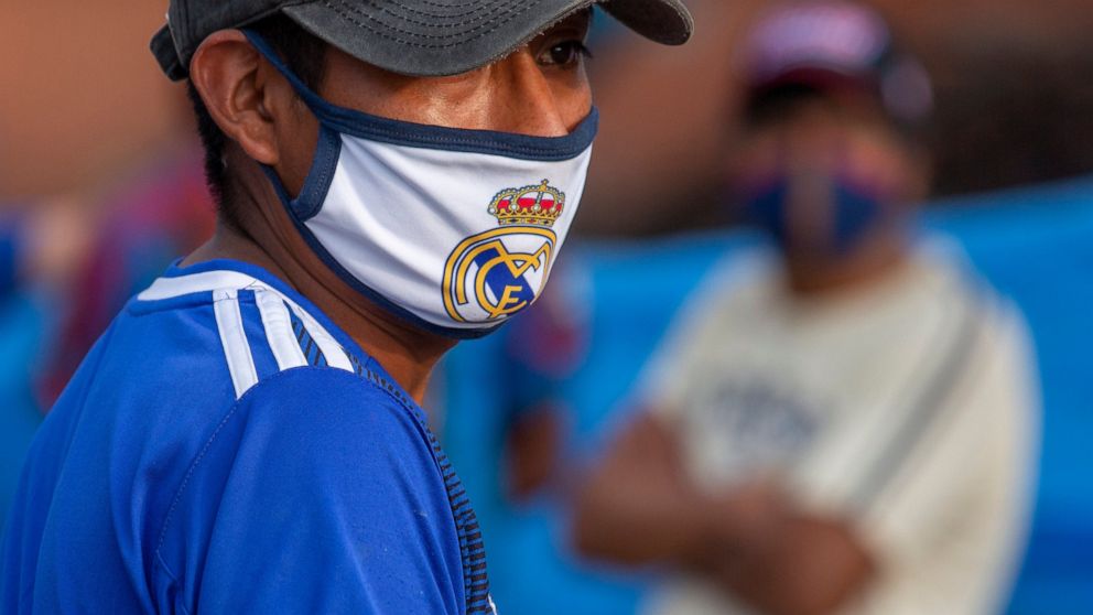 A tomato vendor wears a face mask decorated with the logo of the Spanish soccer team Real Madrid at "La Terminal" market, closed amid lockdown in Guatemala City, early Friday, May 15, 2020. The government decreed a three-day, nationwide lockdown star