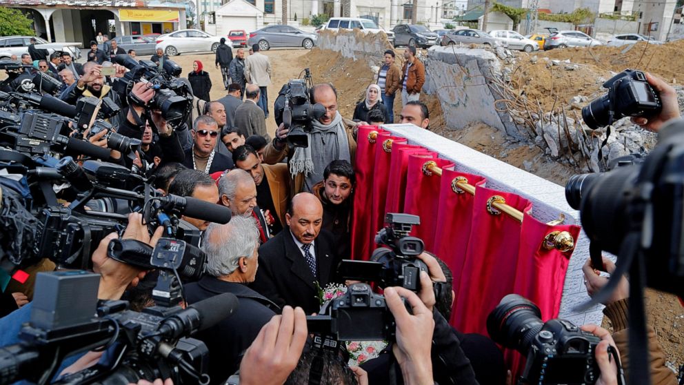 FILE - Video journalists and photographers work as Mufid Hassayneh, Palestinian minister of public works, center, and Mohammed Abu Haloub of Qatar Charity, unseen, speaks during a cornerstone ceremony for rebuilding Zafer 4 Tower in Gaza, in the nort