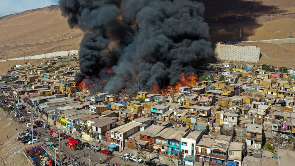 Houses burn during a fire in the low income neighborhood of Laguna Verde, in Iquique, Chile, Monday, Jan. 10, 2022. According to authorities the fire destroyed close to 100 homes of the neighborhood which is populated mostly by migrants. (AP Photo/Ig