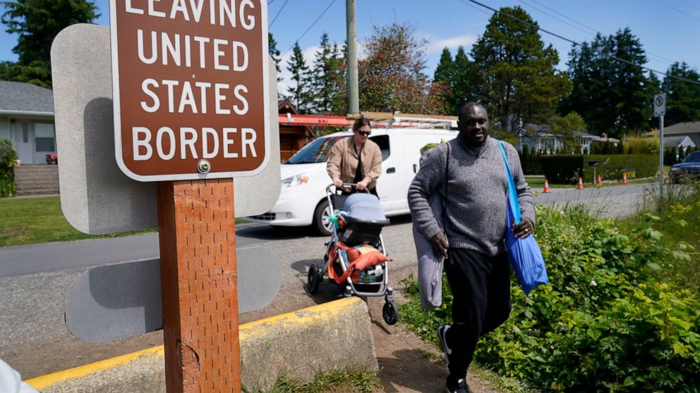 Canadian residents Philip Owira, right, and Katherine Nichol walk with their baby across a small ditch from Canada into Peace Arch Historical State Park to visit a friend there, Tuesday, June 8, 2021, in Blaine, Wash. The border has been closed to no