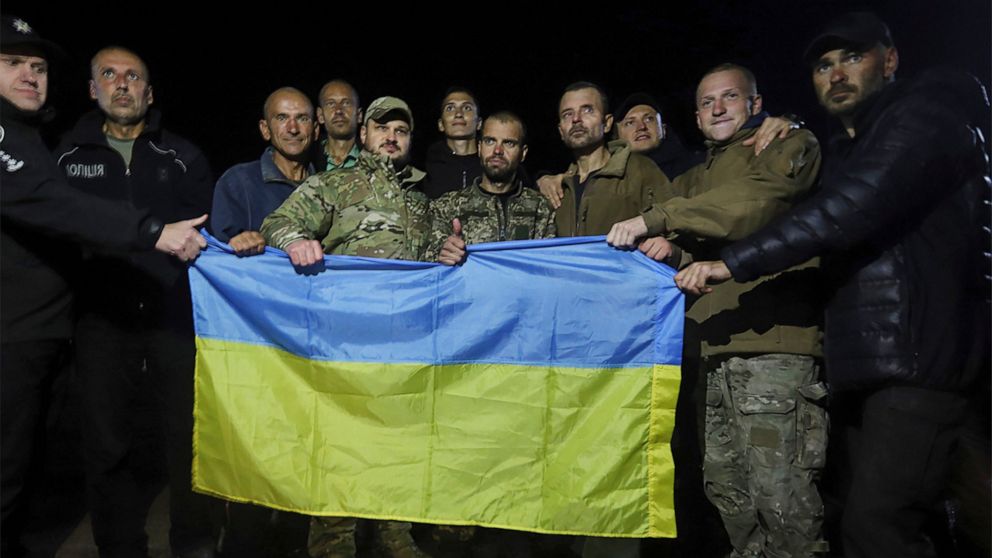 In this photo provided by the Ukrainian Security service Press Office, Ukrainian soldiers released in a prisoner exchange between Russia and Ukraine, hold the Ukrainian flag close to Chernihiv, Ukraine, late Wednesday, Sept. 21, 2022. Ukraine announc
