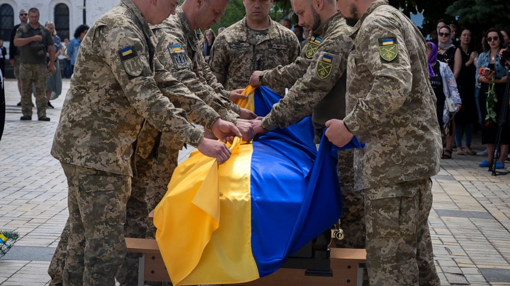 Soldiers fold a Ukrainian flag on the coffin of a soldier, codename Fanat, killed by the Russian troops in a battle, during his funeral at St Michael cathedral in Kyiv, Ukraine, Ukraine, Monday, July 18, 2022. (AP Photo/Efrem Lukatsky)
