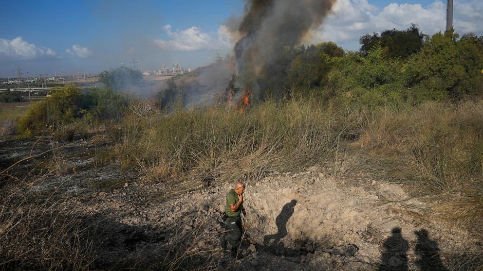 A police officer inspects the area around a fire after the military said it fired interceptors at a missile launched from Yemen that landed in central Israel on Sunday, Sept. 15, 2024. (AP Photo/Ohad Zwigenberg)