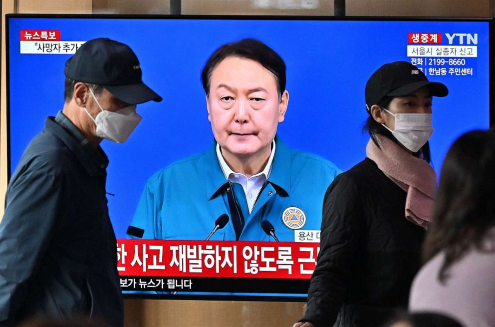 PHOTO: People watch a television news programme broadcasting live footage of South Korean President Yoon Suk-yeol delivering a speech on the deadly Halloween stampede, at a railway station in Seoul on October 30, 2022.  