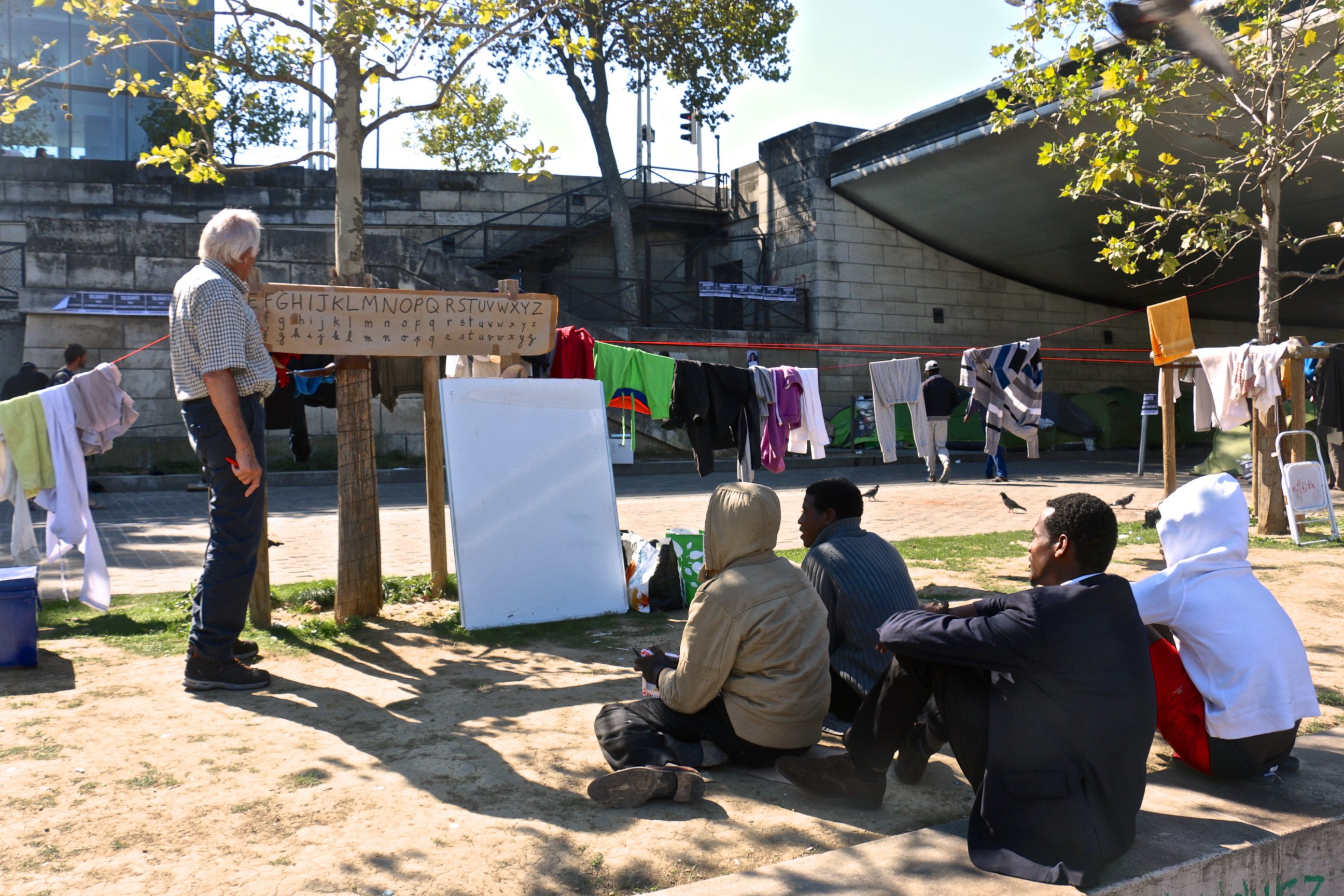 PHOTO: A volunteer teaches French to migrants and refugees living in tents at Austerlitz, near the Seine River in Paris, Sept. 10, 2015.