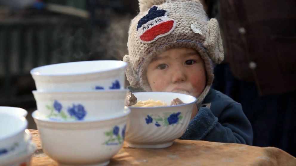 PHOTO: A young child eats lunch inside a Kashgar marketplace in Xinjiang, China in December 2015. 