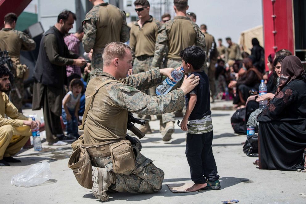 PHOTO: A Marine with the 24th Marine Expeditionary Unit (MEU) provides fresh water to a child during an evacuation at Hamid Karzai International Airport, Kabul, Aug. 20, 2021.
