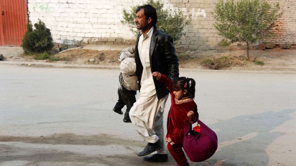 PHOTO: An Afghan man runs with two children near an office of the British charity Save the Children during an attack in Jalalabad, Jan. 24, 2018.