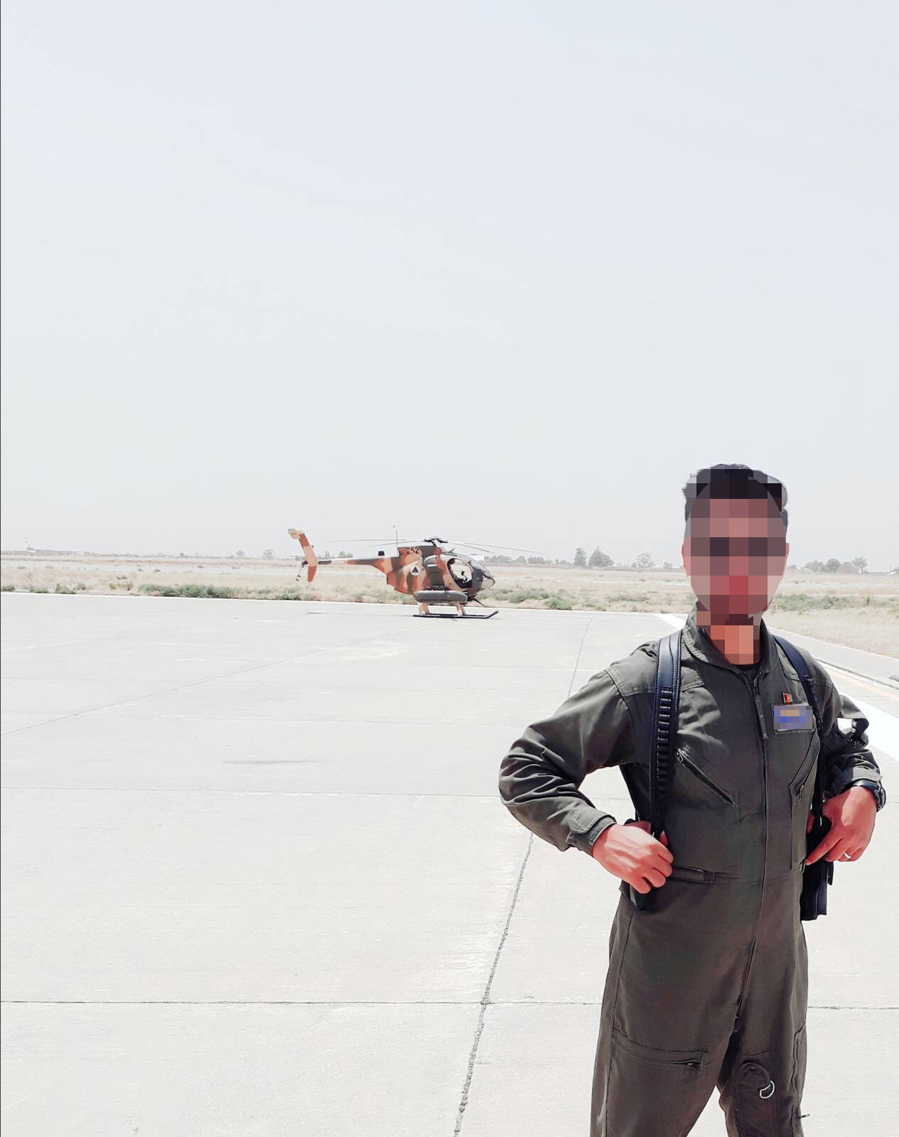 PHOTO: One of the pilots stands at an airfield in Afghanistan, with a helicopter in the background.