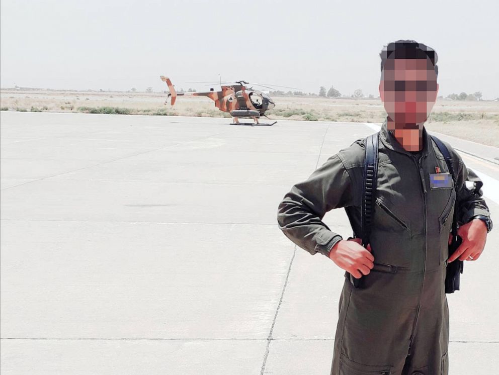 PHOTO: One of the pilots stands at an airfield in Afghanistan, with a helicopter in the background.