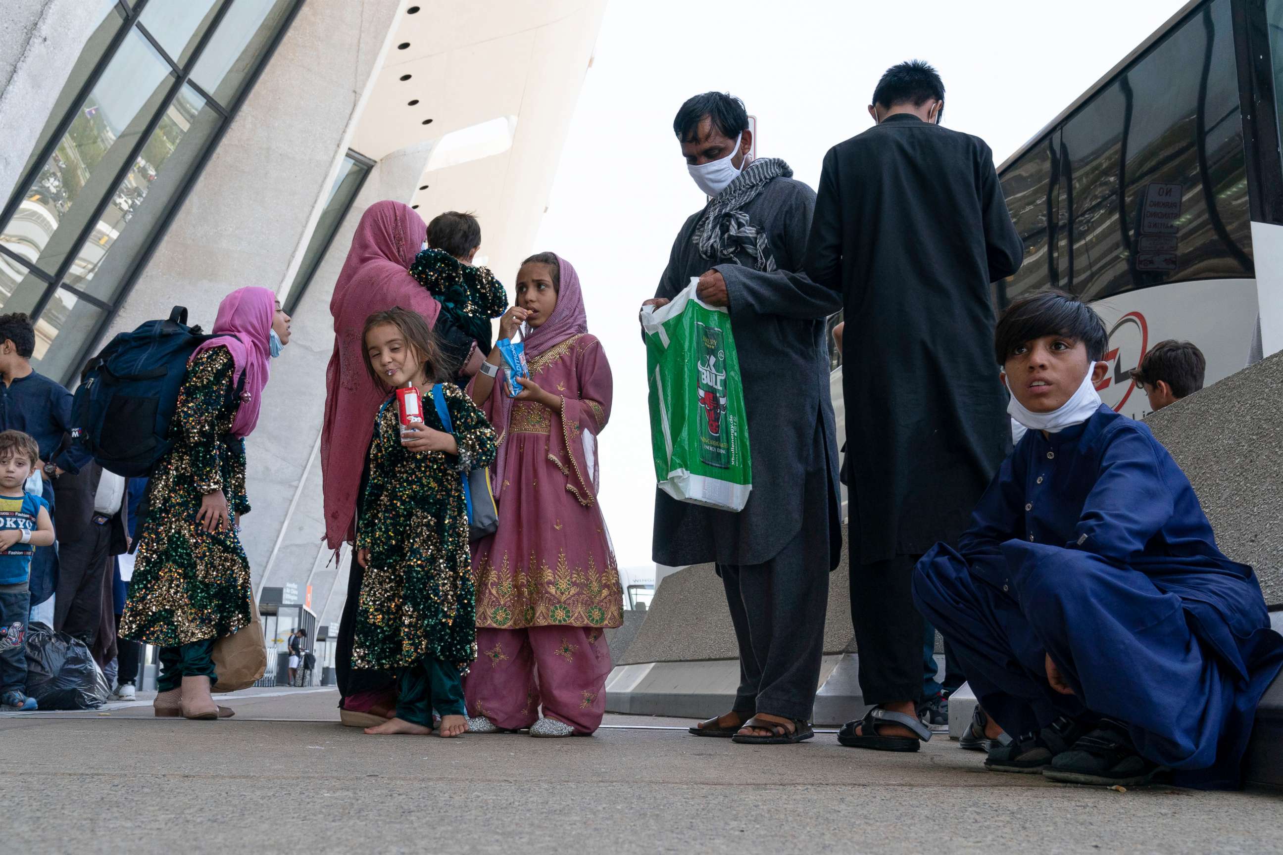 PHOTO: Families evacuated from Kabul, Afghanistan, wait outside the terminal to board a bus after they arrived at Washington Dulles International Airport, in Chantilly, Va., Aug. 24, 2021.