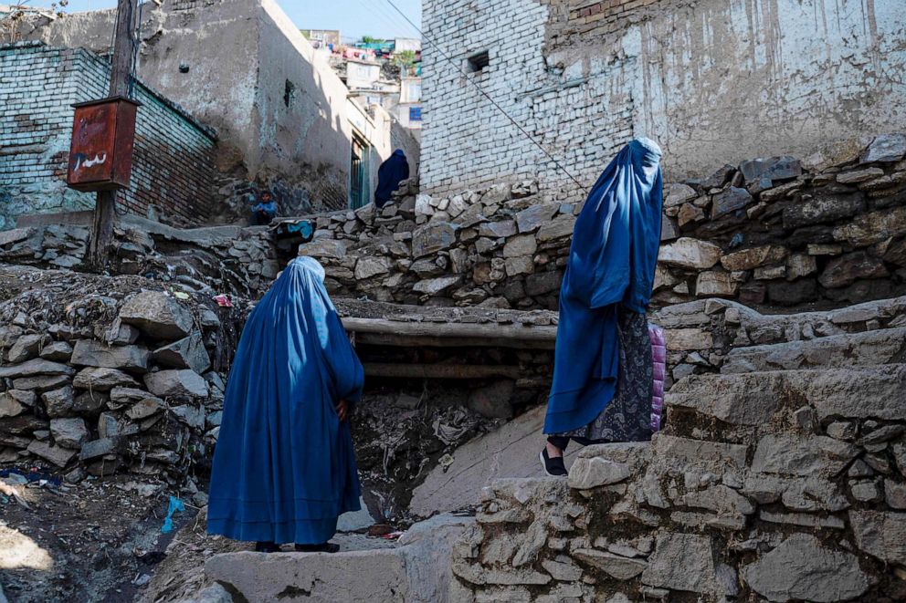 PHOTO: Afghan burqa-clad women climb a stony path in Kabul on April 6, 2023.