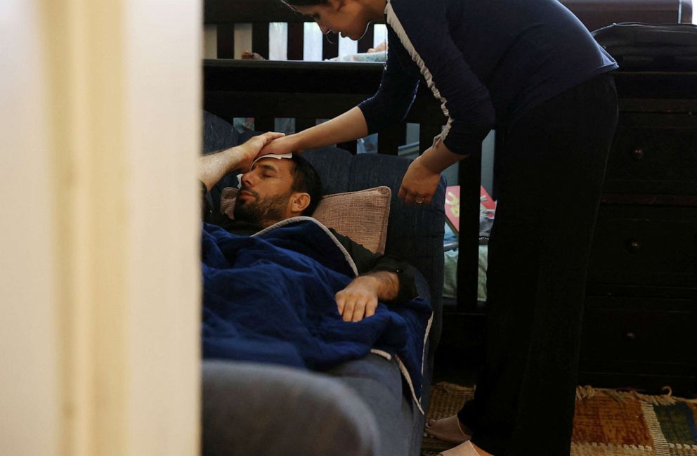 PHOTO: Susan Mohammadi wipes her husband Najib Mohammadi's forehead as he rests on the sofa after having had an emergency appendectomy hours earlier in Sacramento, Calif., July 21, 2022.