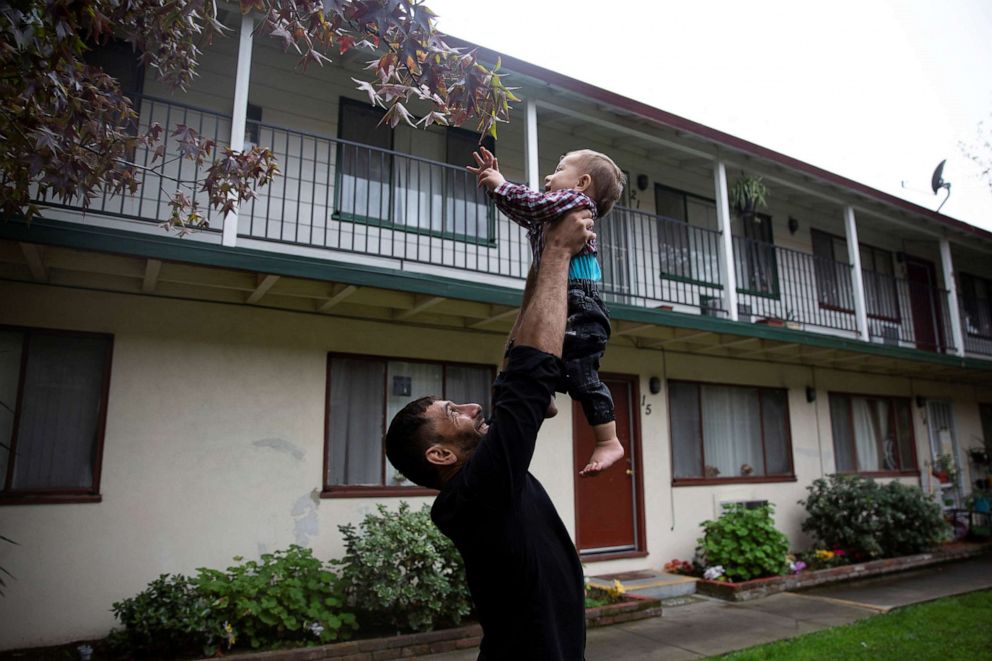 PHOTO: Najib Mohammadi holds his son Yasar Mohammadi in the air to play with leaves outside their apartment in Sacramento, Calif., Nov. 13, 2021.