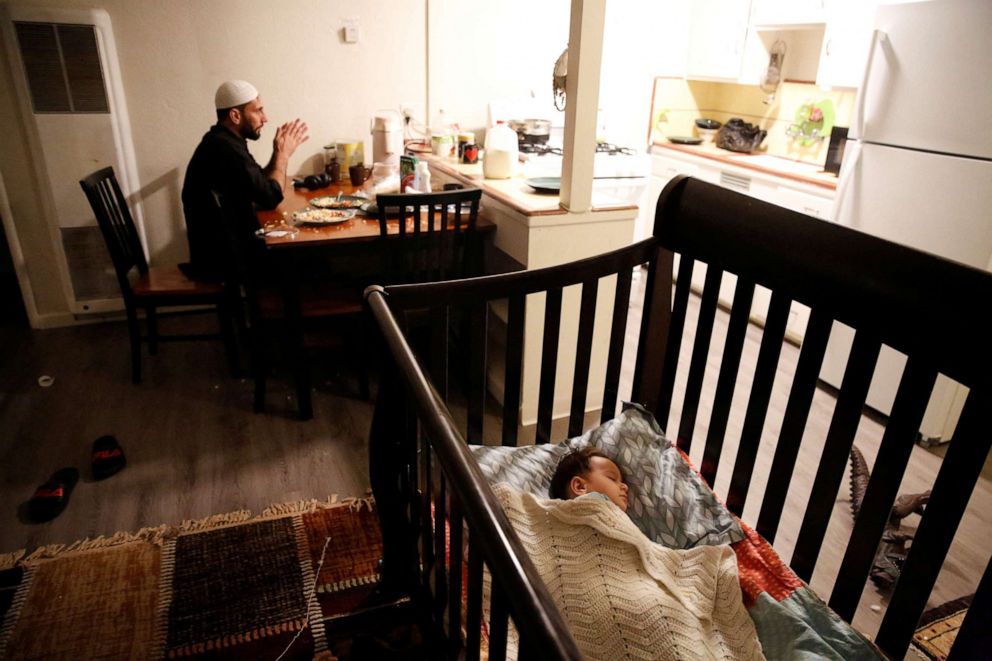 PHOTO: Najib Mohammadi sits at the dining table while his son Yasar Mohammadi, 1, sleeps in a cot in the living room of their apartment in Sacramento, Calif., March 27, 2022.