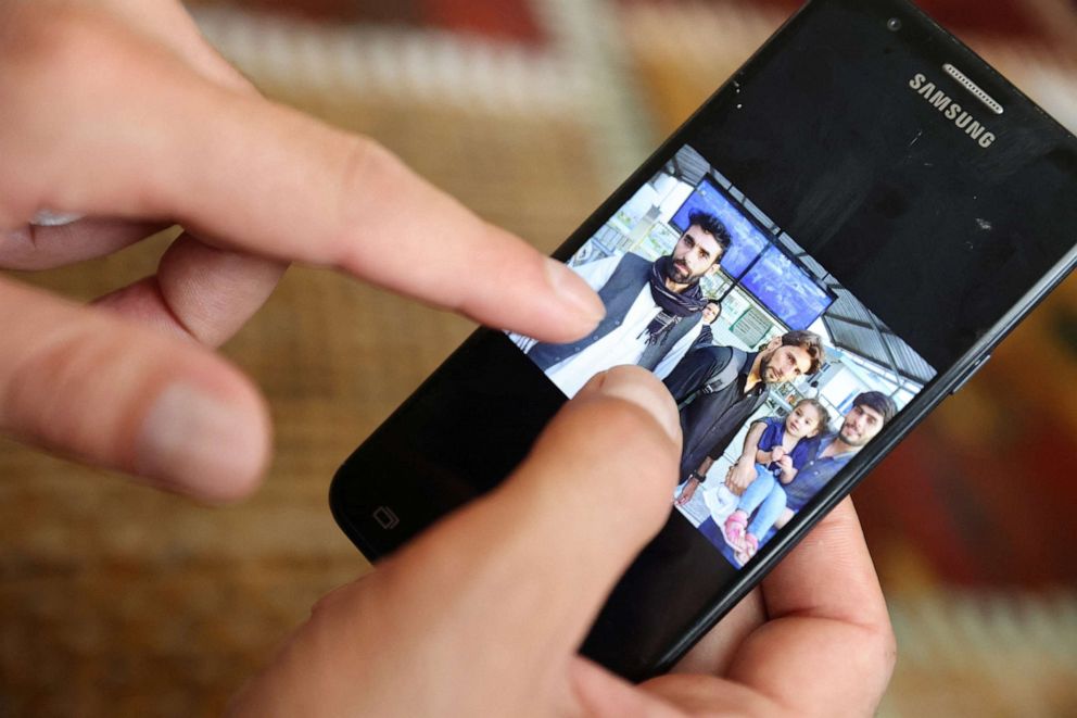 PHOTO: Najib Mohammadi points out family members in a photo taken on the day he and his wife Susan Mohammadi left Afghanistan for the U.S., on his phone, at his home in Sacramento, Calif, Aug. 1, 2022.
