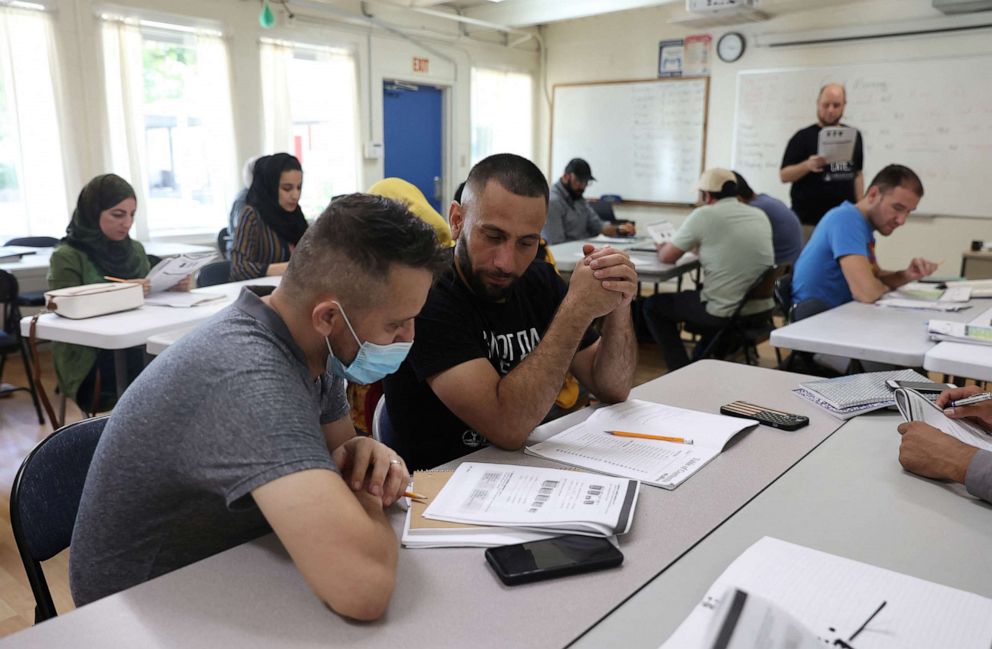 PHOTO: Najib Mohammadi ,center, talks with a classmate during a vocabulary lesson at the Highlands Adult Charter School where he attends classes in Sacramento, Calif., June 7, 2022.