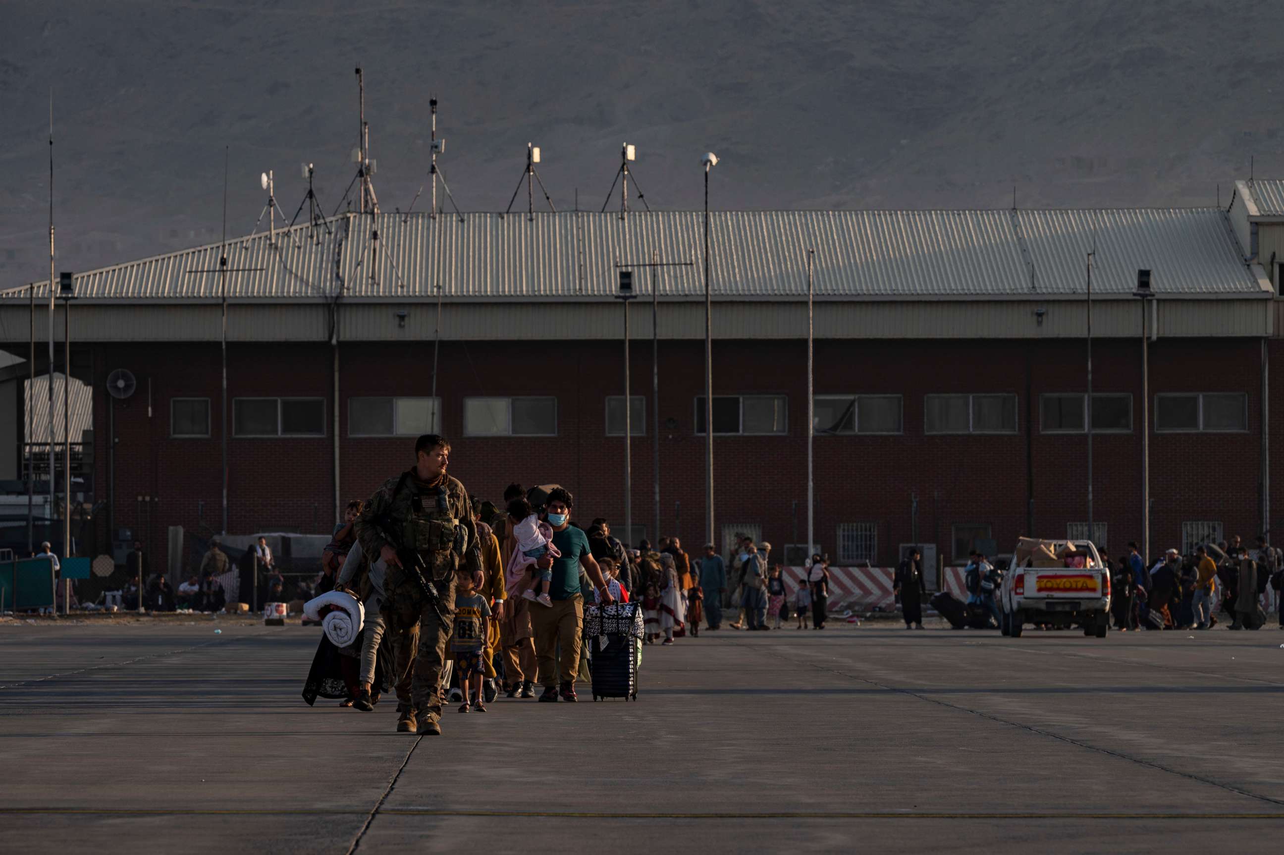 PHOTO: A U.S. Air Force Airman guides evacuees toward a U.S. Air Force C-17 plane during evacuations from Hamid Karzai International Airport in Afghanistan, Aug. 24, 2021.