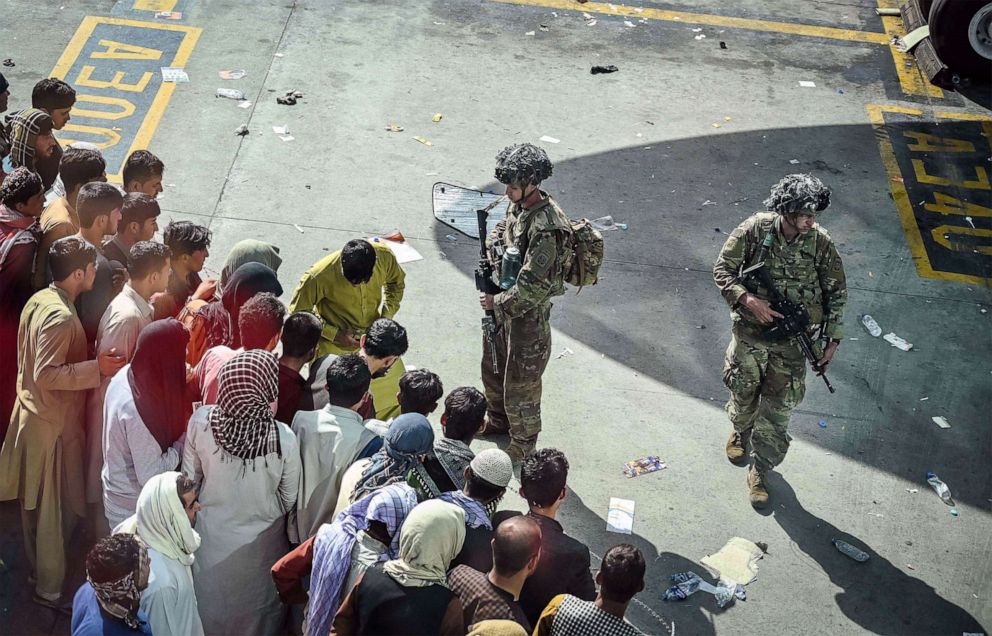 PHOTO: U.S. soldiers stand guard as people wait in the hopes of evacuating at the Kabul airport in Kabul, Afghanistan, Aug. 16, 2021.