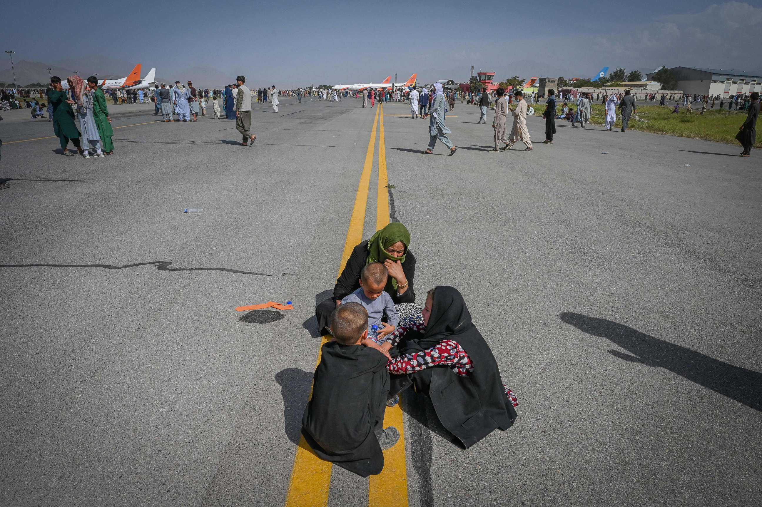 PHOTO: Afghan people sit along the tarmac as they wait to leave the Kabul airport in Kabul, Afghanistan, Aug. 16, 2021.