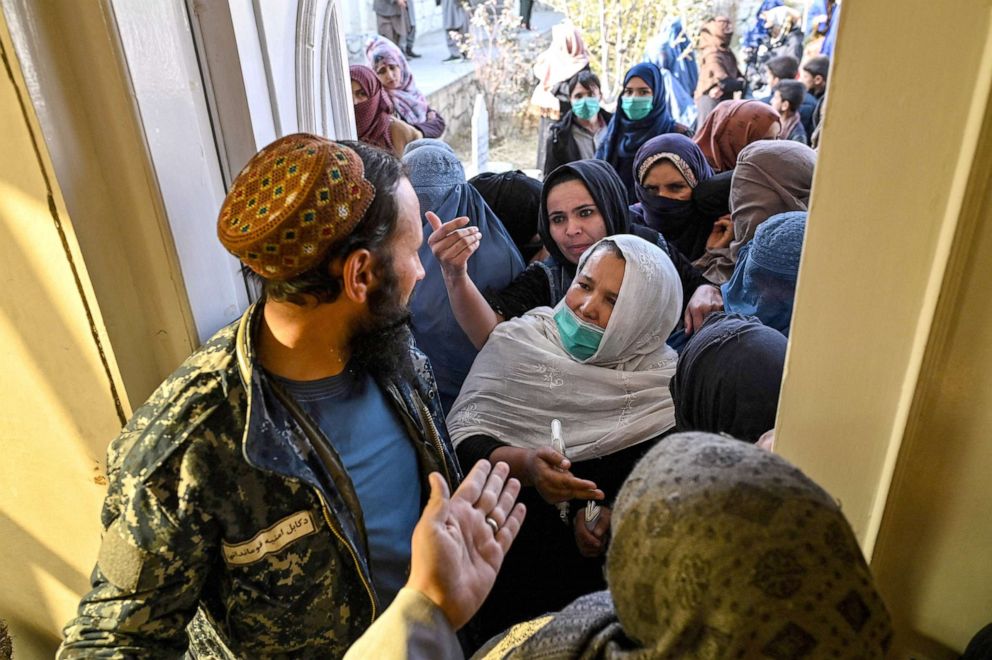 PHOTO: A Taliban fighter guards an entrance as women wait in a queue during a World Food Programme cash distribution event in Kabul, Nov. 29, 2021. 