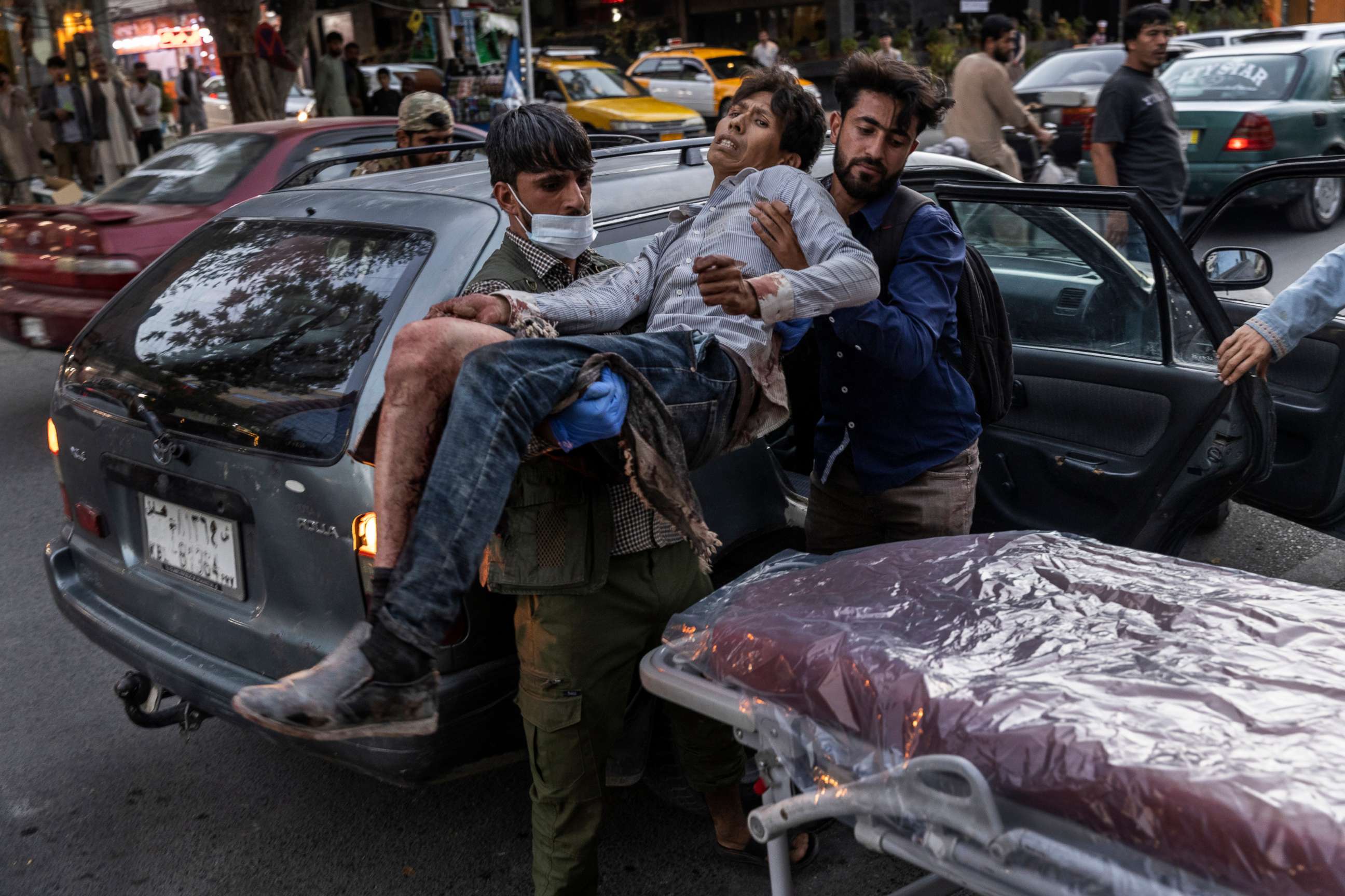 PHOTO: People assist a person wounded in a bomb blast outside the Kabul airport in Afghanistan, Aug. 26, 2021, at a hospital in Kabul.