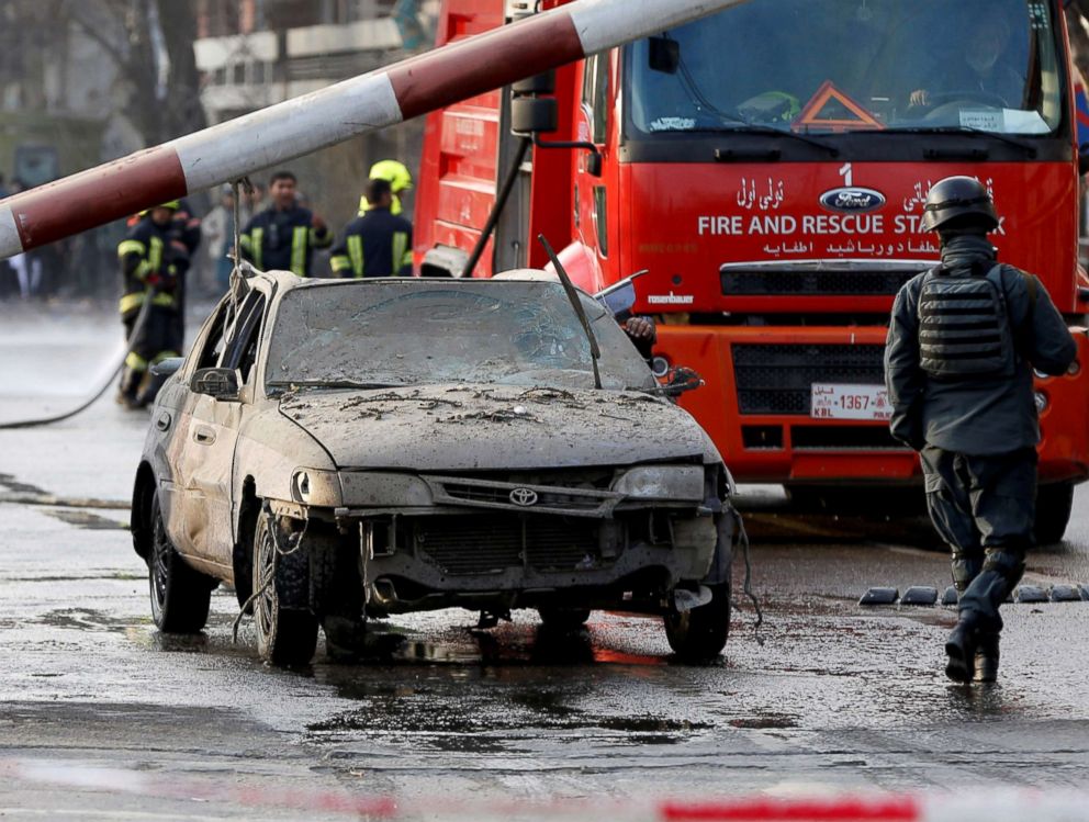 PHOTO: Police officers keep watch while a man drives his heavily damaged car at a car bomb attack site in Kabul, Afghanistan, Jan. 27, 2018.