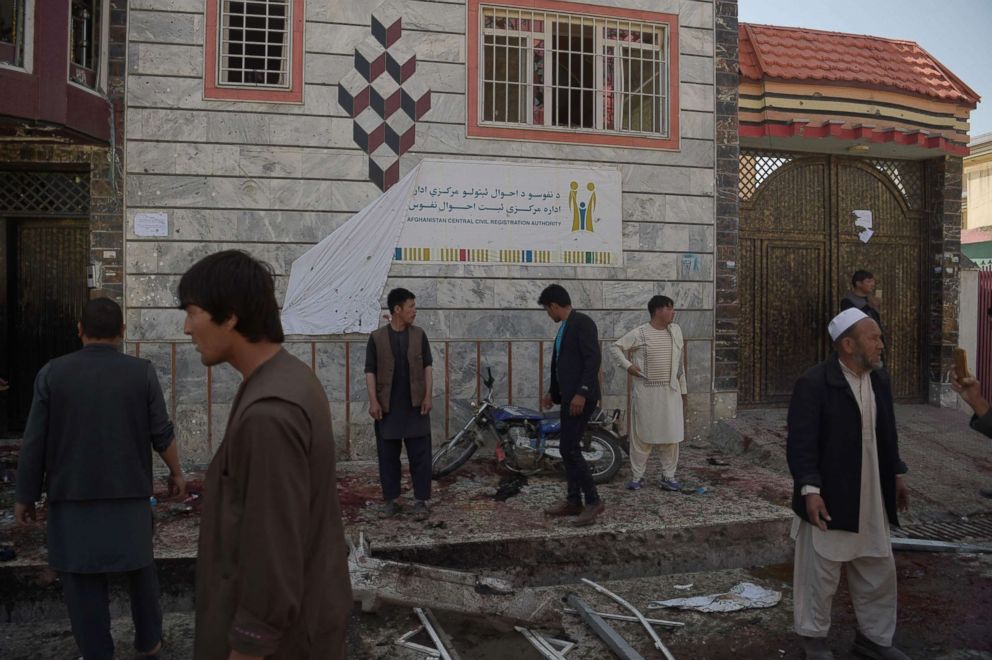 PHOTO: Afghan residents inspect the site of a suicide bombing outside a voter registration center in Kabul, April 22, 2018.