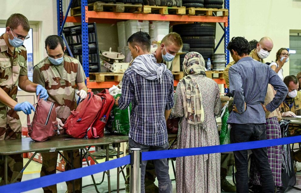 PHOTO: People have their luggages checked by soldiers in a reunion and evacuation center at the French military air base 104 of Al Dhafra, near Abu Dhabi, on Aug. 23, 2021, after being evacuated from Kabul as part of the operation "Apagan".