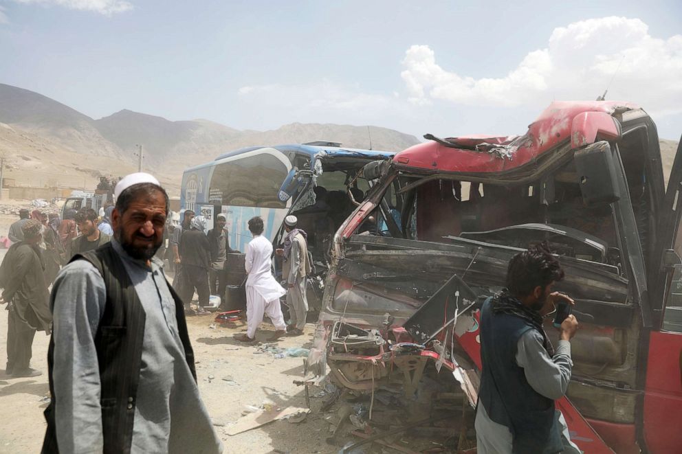 PHOTO: Afghan men stand near damaged buses after a deadly accident on the Kabul-Kandahar highway, on the outskirts of Kabul, Afghanistan, April 27, 2021. 