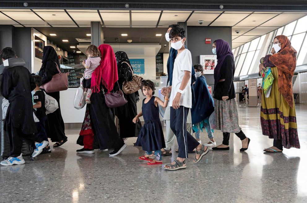 PHOTO: Refugees from Afghanistan are escorted to a waiting bus after arriving and being processed at Dulles International Airport in Dulles, Va., Aug. 23, 2021.  