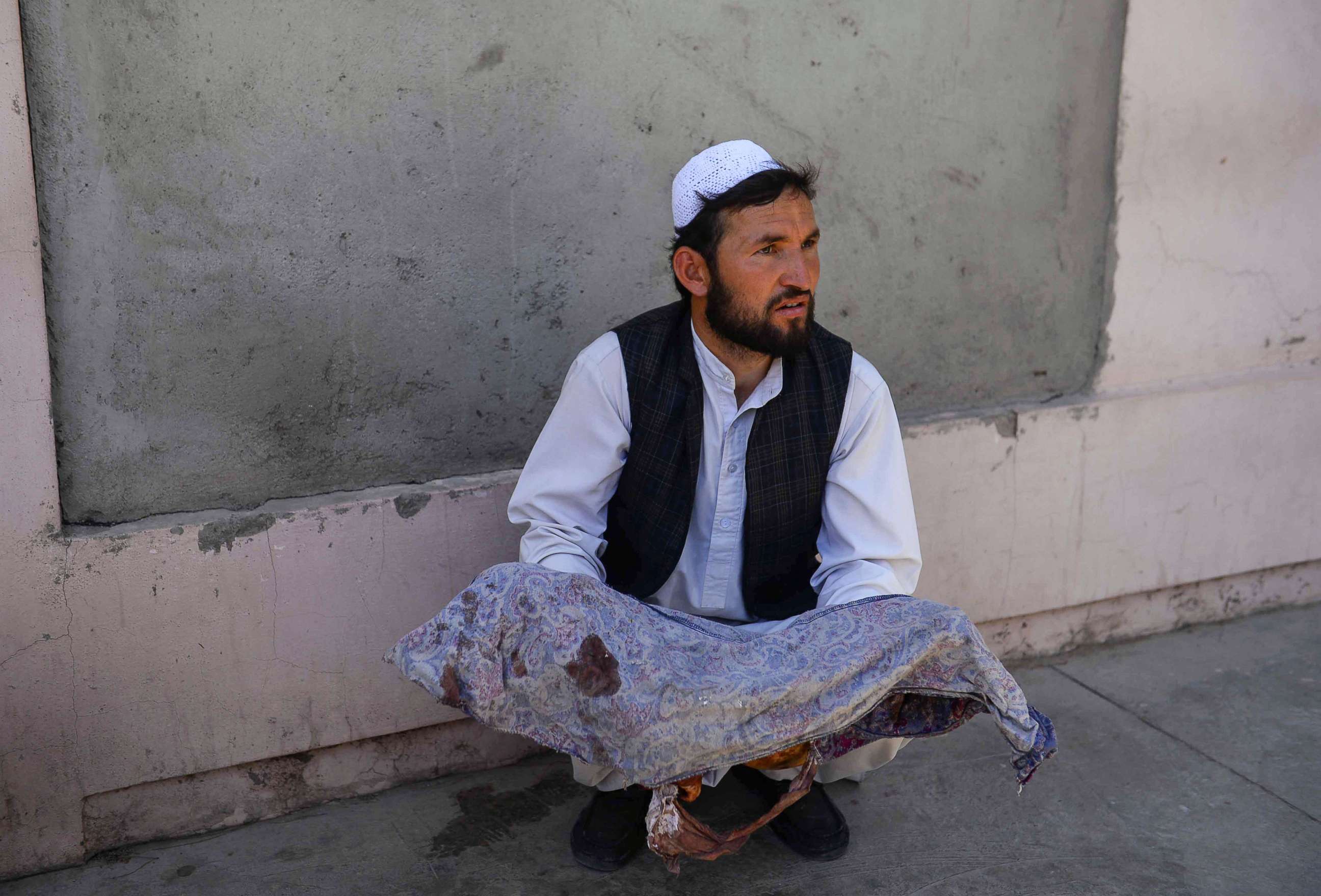 PHOTO: An Afghan man holds the body of a child killed when a bus hit a roadside bomb on the Kandahar-Herat highway, at a hospital in Herat on July 31, 2019.