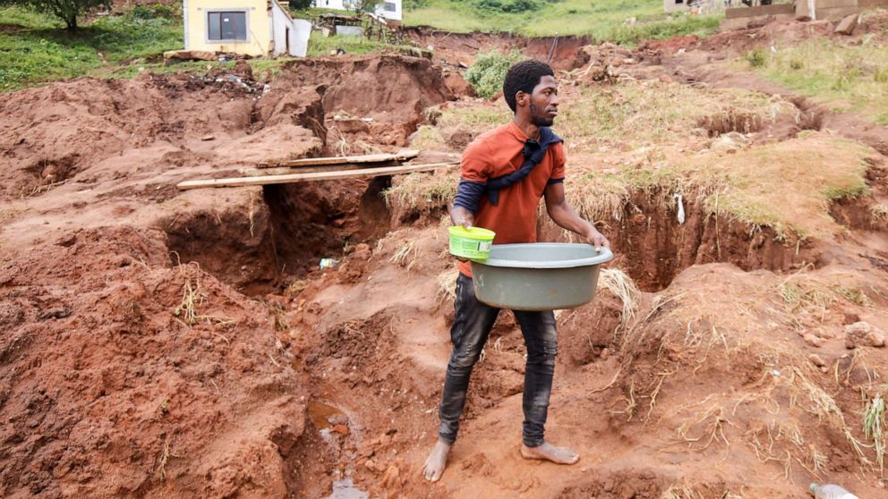 PHOTO: Mthandi Sibiya collects water near what remains of his home which collapsed while he was sleeping due flooding in Mzinyathi near Durban, South Africa, April 17, 2022.