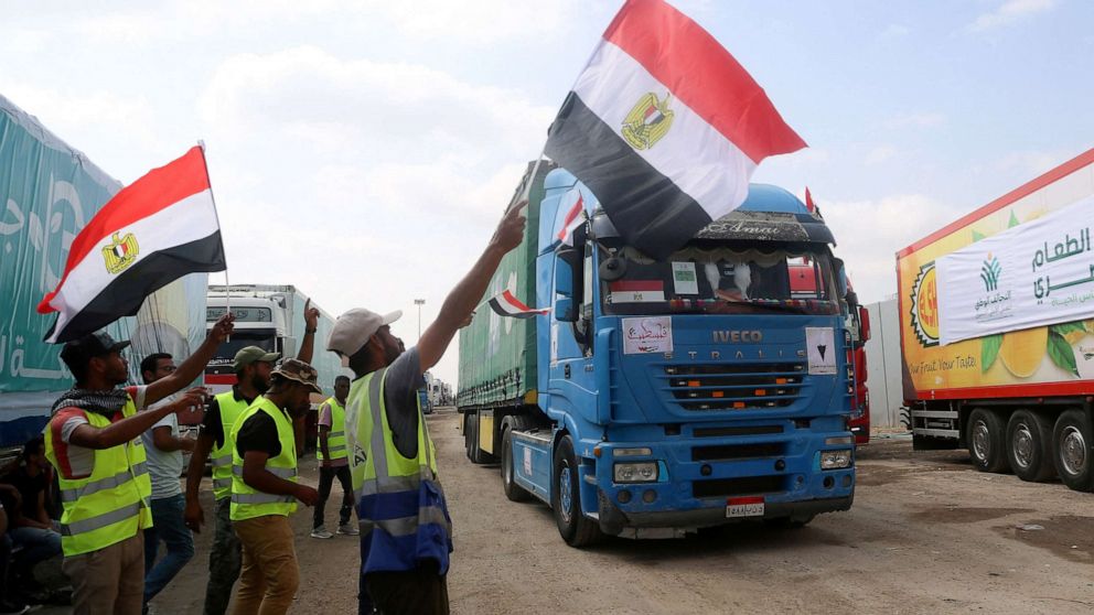 PHOTO: People on the Egyptian side of the Rafah border crossing wave flags as a convoy of lorries carrying humanitarian aid crosses to the Gaza Strip on Oct. 22, 2023.